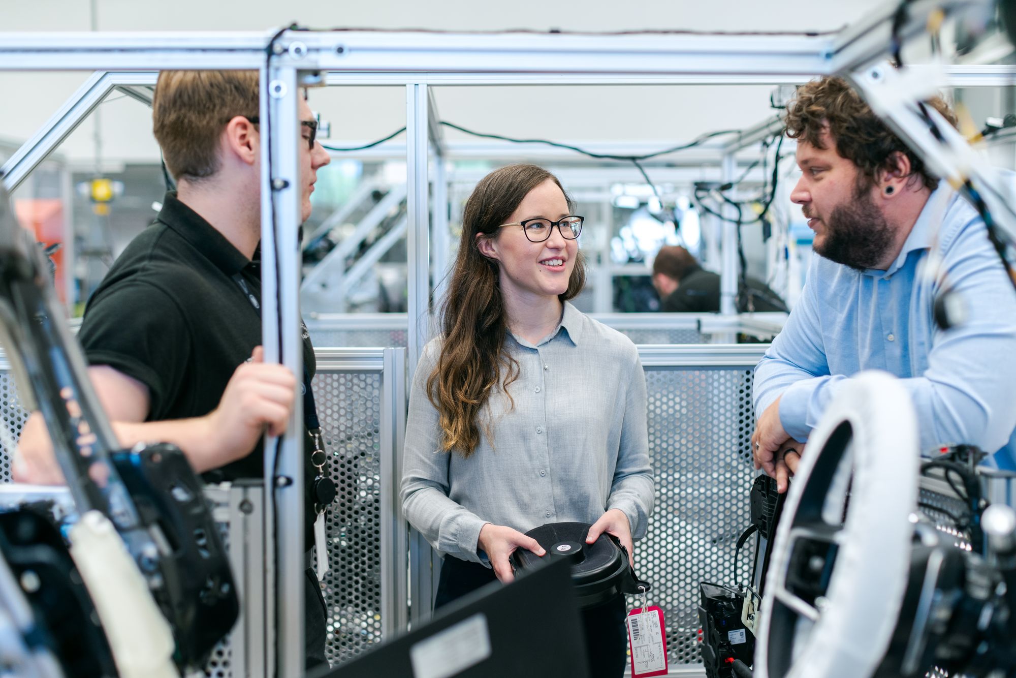 Drei technische Fachkräfte im Gespräch in einer Produktionshalle